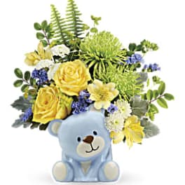 Yellow and white flower arrangement in a blue teddy bear container