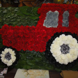 Floral arrangement shaped like a red truck with white wheels