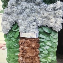 Large floral standing spray with silver-gray blooms and green foliage
