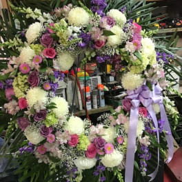 Large floral wreath with pink, purple, and white flowers and a lavender ribbon