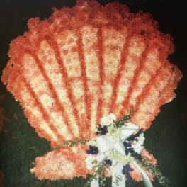 Orange carnation standing spray with white ribbon and blue accents