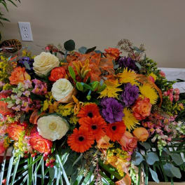 Large colorful floral arrangement with roses, gerbera daisies, and ribbon