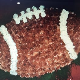 Football-shaped floral arrangement in brown and white flowers