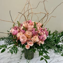 Pink roses and snapdragons in a glass vase with curly branches