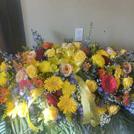 Large colorful floral spray with roses, daisies, and ribbon