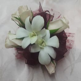 White orchid and rose corsage with burgundy ribbon accents