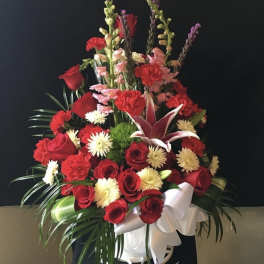 Red and white floral arrangement in a white vase with a ribbon