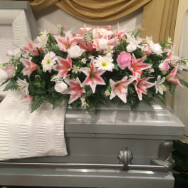 Floral casket spray with pink and white flowers on a gray casket