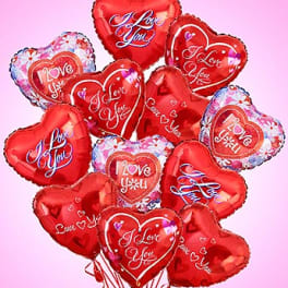 Bouquet of red heart-shaped 'I Love You' foil balloons on a pink background