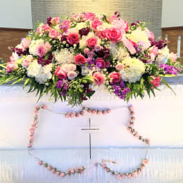 Large pink, white, and purple floral spray on a white casket