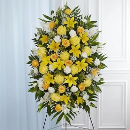 Standing floral spray with yellow lilies, roses, and white blooms