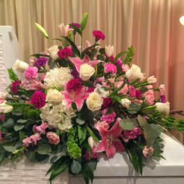 Large pink and white floral arrangement with lilies and roses on a table