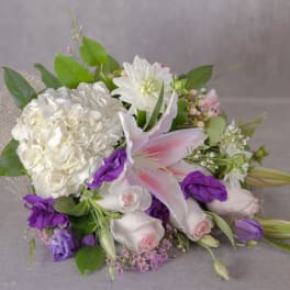 White and purple bouquet with lilies and roses on burlap wrap