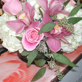 Pink orchids and roses arranged with white hydrangeas in a low vase