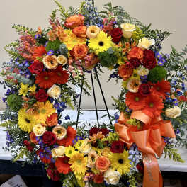 Large floral wreath with roses, gerbera daisies, and mixed blooms on a stand