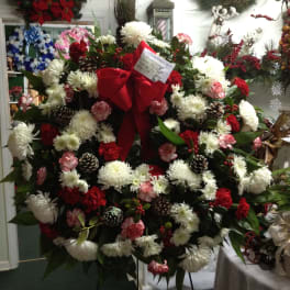 Large holiday wreath with white and red flowers and a red bow