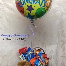 Congrats balloon above a basket of snacks with a teddy bear