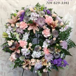 Pastel floral wreath with pink, lavender, and white blooms on an easel