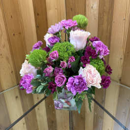 Pink and purple flower arrangement in a square glass vase