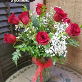 Red roses arranged in a clear glass vase with baby's breath