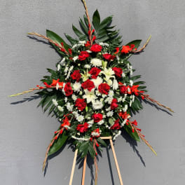 Standing floral spray with red roses, white lilies, and daisies on an easel