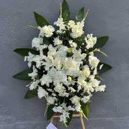 White funeral spray on an easel with a ribbon