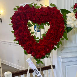 Heart-shaped red rose arrangement on an easel with a white rose cluster beside it