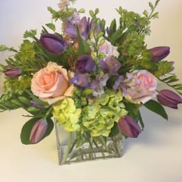 Bouquet of pink roses, purple tulips, and green hydrangeas in a glass vase