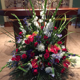 Large floral arrangement with red roses, white gladiolus, and anthuriums