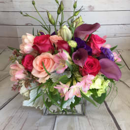 Mixed bouquet of roses, calla lilies, and lilies in a glass vase