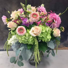 Pink and cream flowers in a glass vase with green hydrangeas