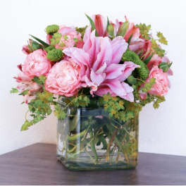 Pink lilies and roses arranged in a square glass vase