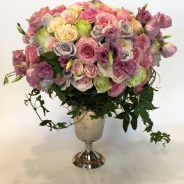 Large pastel rose arrangement in a silver pedestal vase