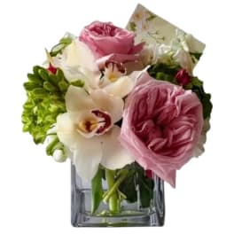Pink roses and white orchids arranged in a clear glass vase