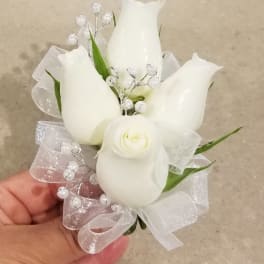 Small white floral corsage with ribbon and pearl accents