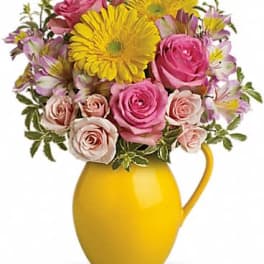 Pink roses and yellow daisies in a yellow pitcher vase