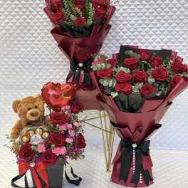 Bouquets of red roses with a teddy bear and heart-shaped chocolate box