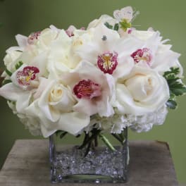 White floral bouquet in a square glass vase with crystal filler