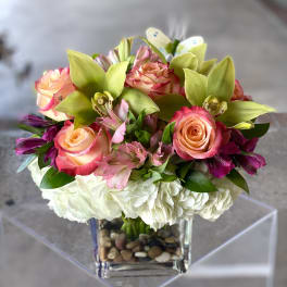 Bouquet of pink roses, orchids, and white hydrangeas in a glass vase