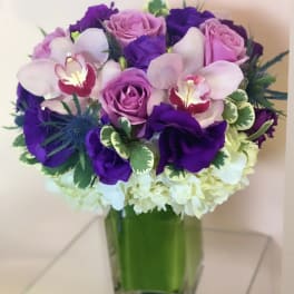 Purple and pink bouquet in a square glass vase