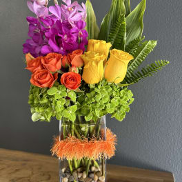 Colorful bouquet of orchids and roses in a glass vase with orange trim