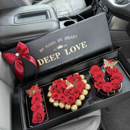 Red roses and chocolates arranged in a black gift box with a ribbon