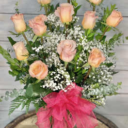 Pink roses and peach roses arranged with baby's breath in a glass vase