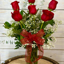 Bouquet of red roses with baby's breath in a glass vase and red ribbon