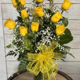 Yellow roses in a glass vase with baby's breath and a yellow ribbon