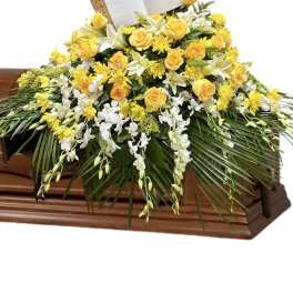 Yellow and white floral casket spray with a Holy Bible card