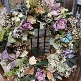 Floral wreath with purple and cream roses and a blue butterfly accent