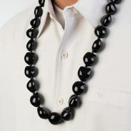 Glossy black beaded lei-style necklace worn over a white shirt