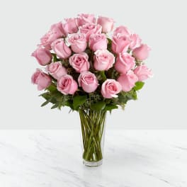 Tall clear vase filled with a large bouquet of light pink roses