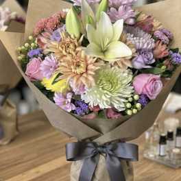 Mixed pastel bouquet with lilies and roses wrapped in brown paper